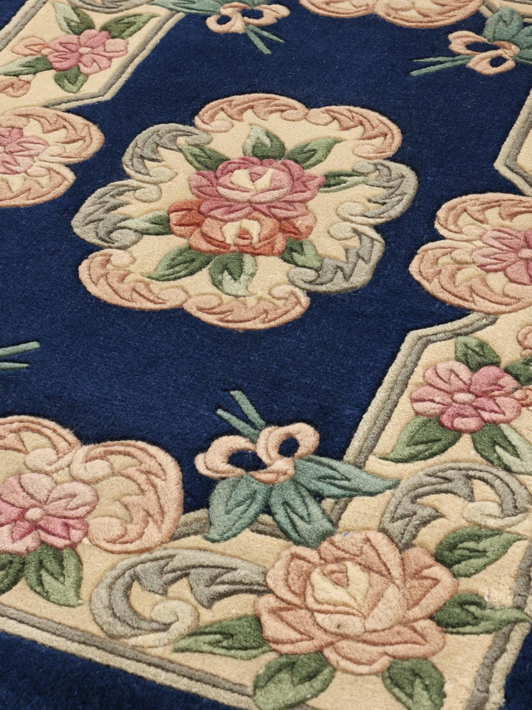 Håndknyttet kinesisk tæppe med blomstermotiver i blå og beige.