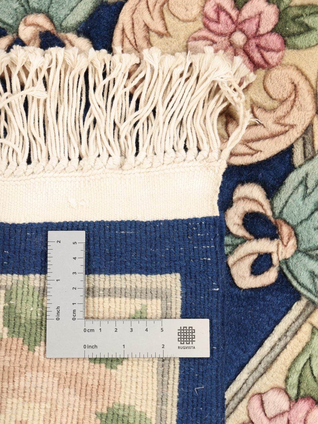 Håndknyttet kinesisk tæppe med blomstermotiver i blå og beige.