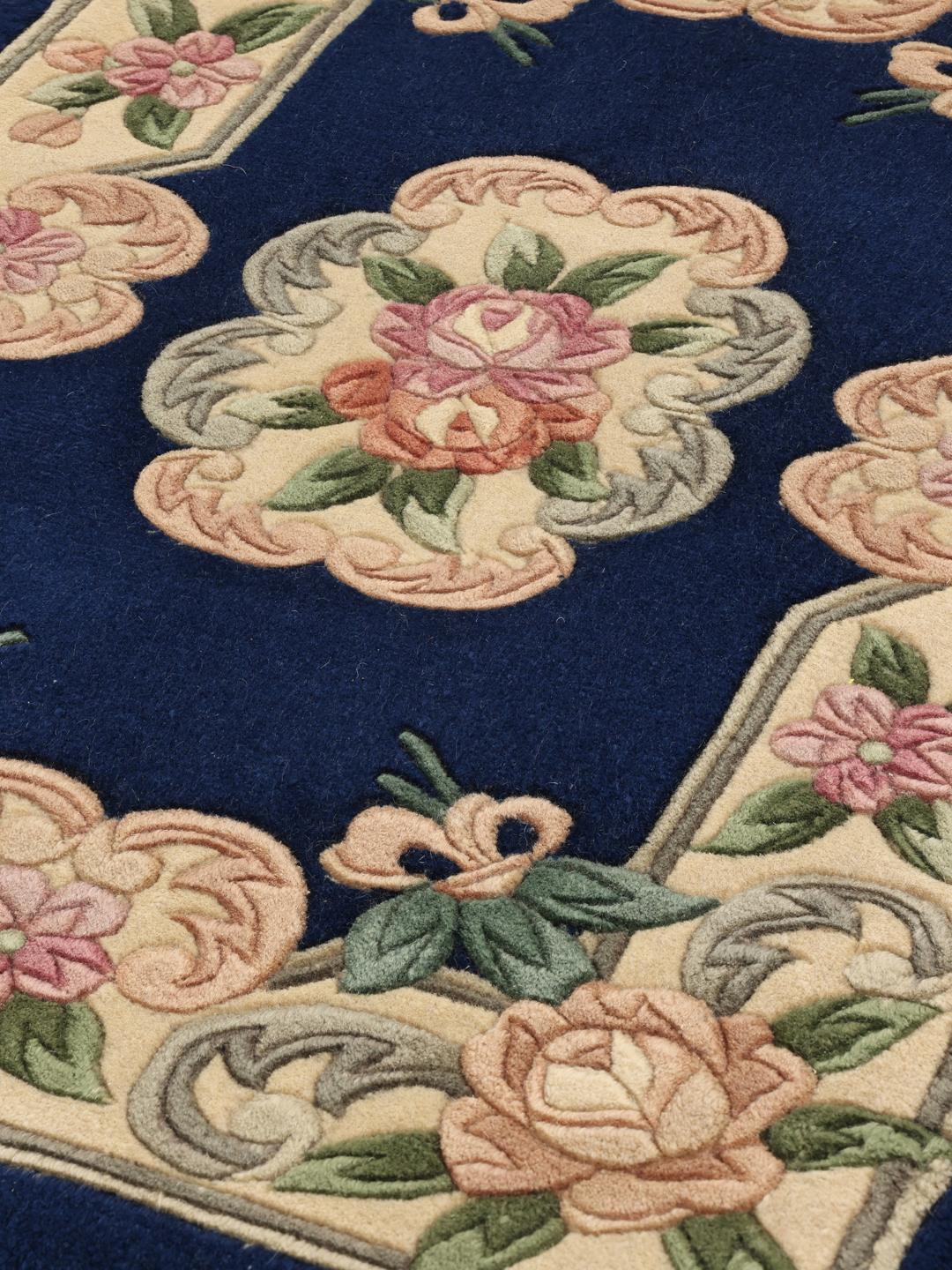 A hand-knotted floral rug from China with a deep blue field and pastel rose accents.