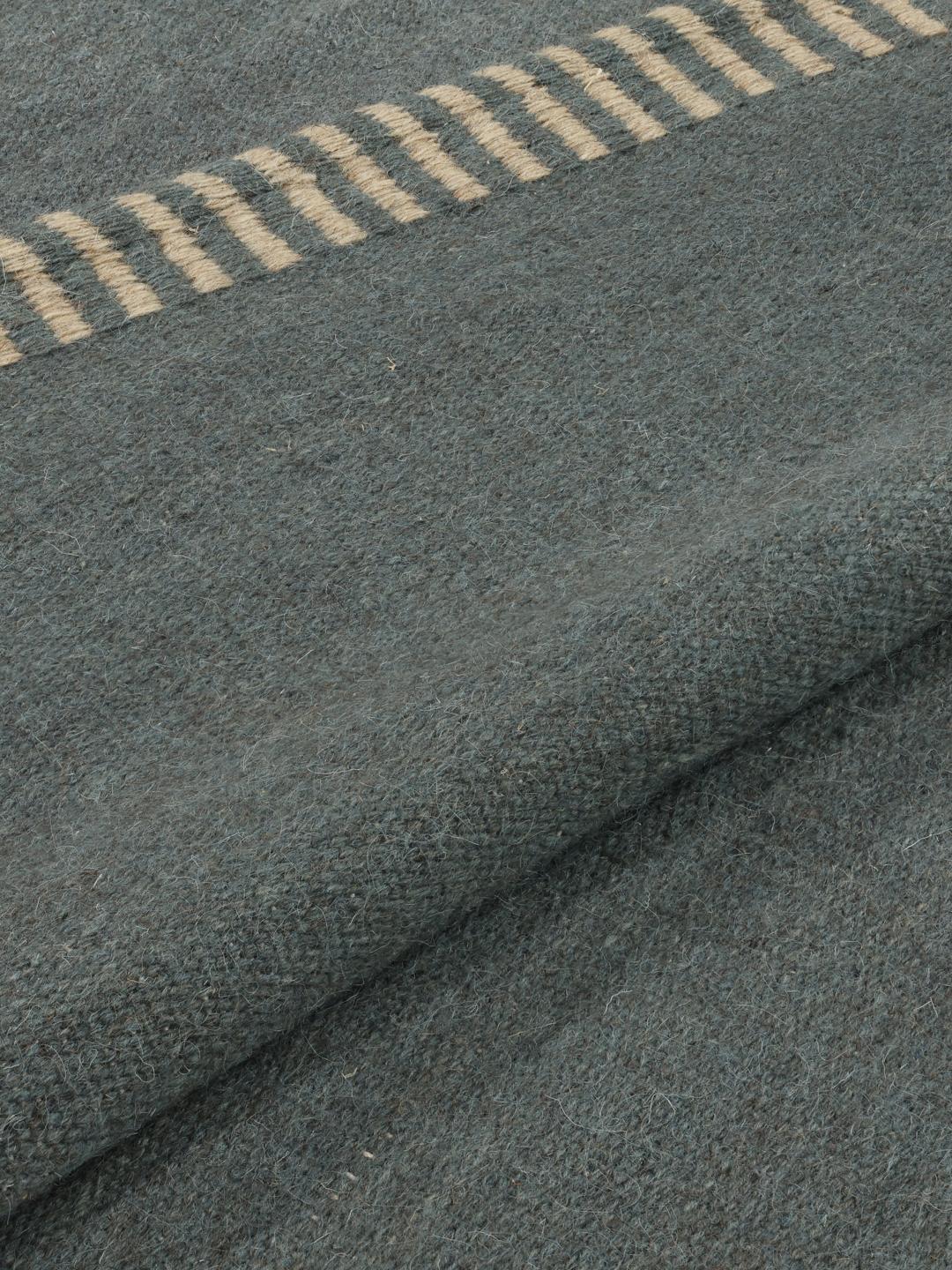 Een vierkant blauw handgeweven tapijt met decoratieve gestreepte randen.