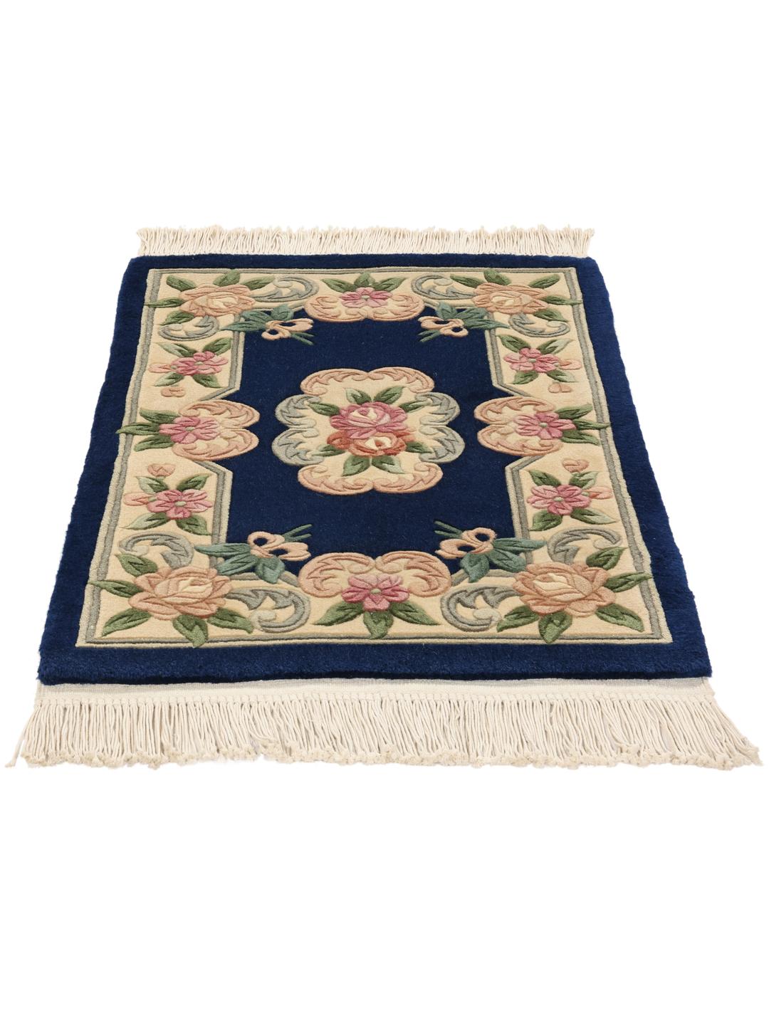 A rectangular hand-knotted rug from China featuring a deep blue field with floral motifs in shades of pink and beige.