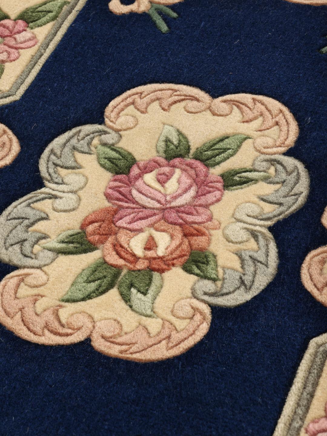 A rectangular hand-knotted rug from China featuring a deep blue field with floral motifs in shades of pink and beige.