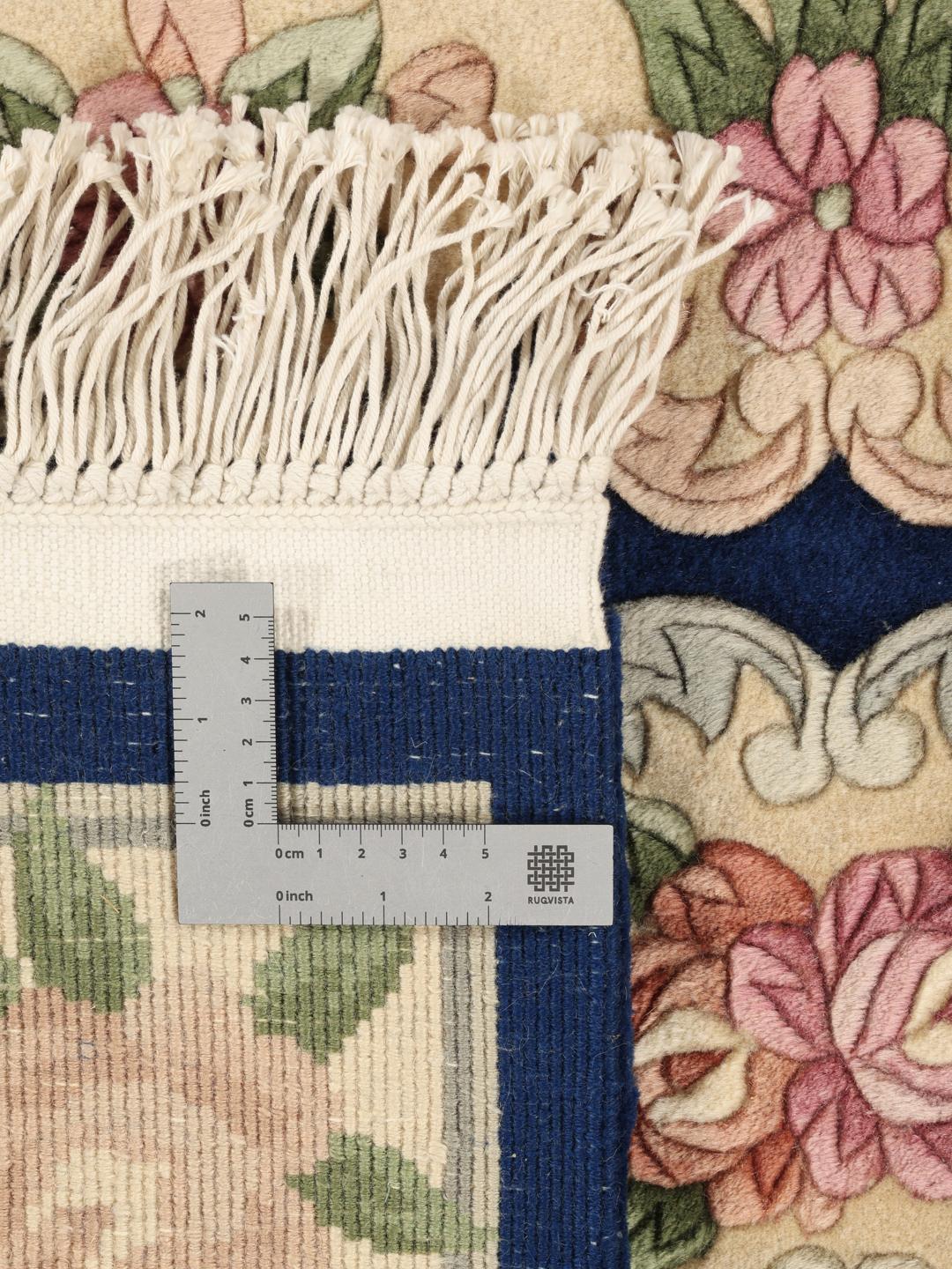 A rectangular hand-knotted rug from China featuring a deep blue field with floral motifs in shades of pink and beige.