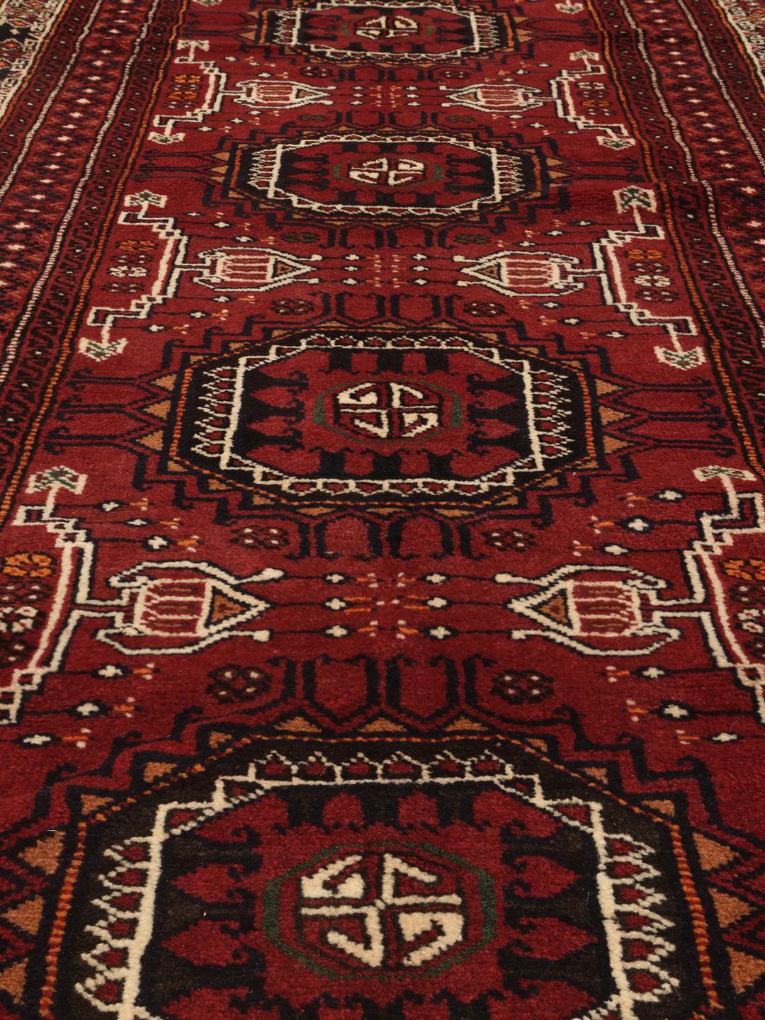 Håndknyttet mellemøstlig løber med geometriske motiver i rød uld.