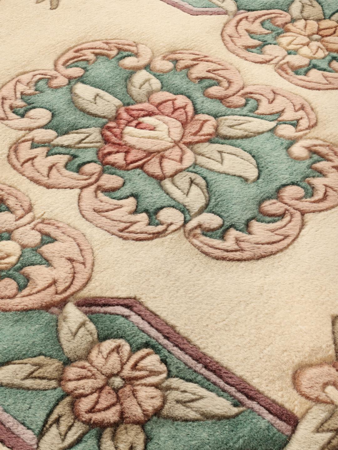 Een rechthoekig handgeknoopt tapijt uit China met een bloemenpatroon in beige en groen.