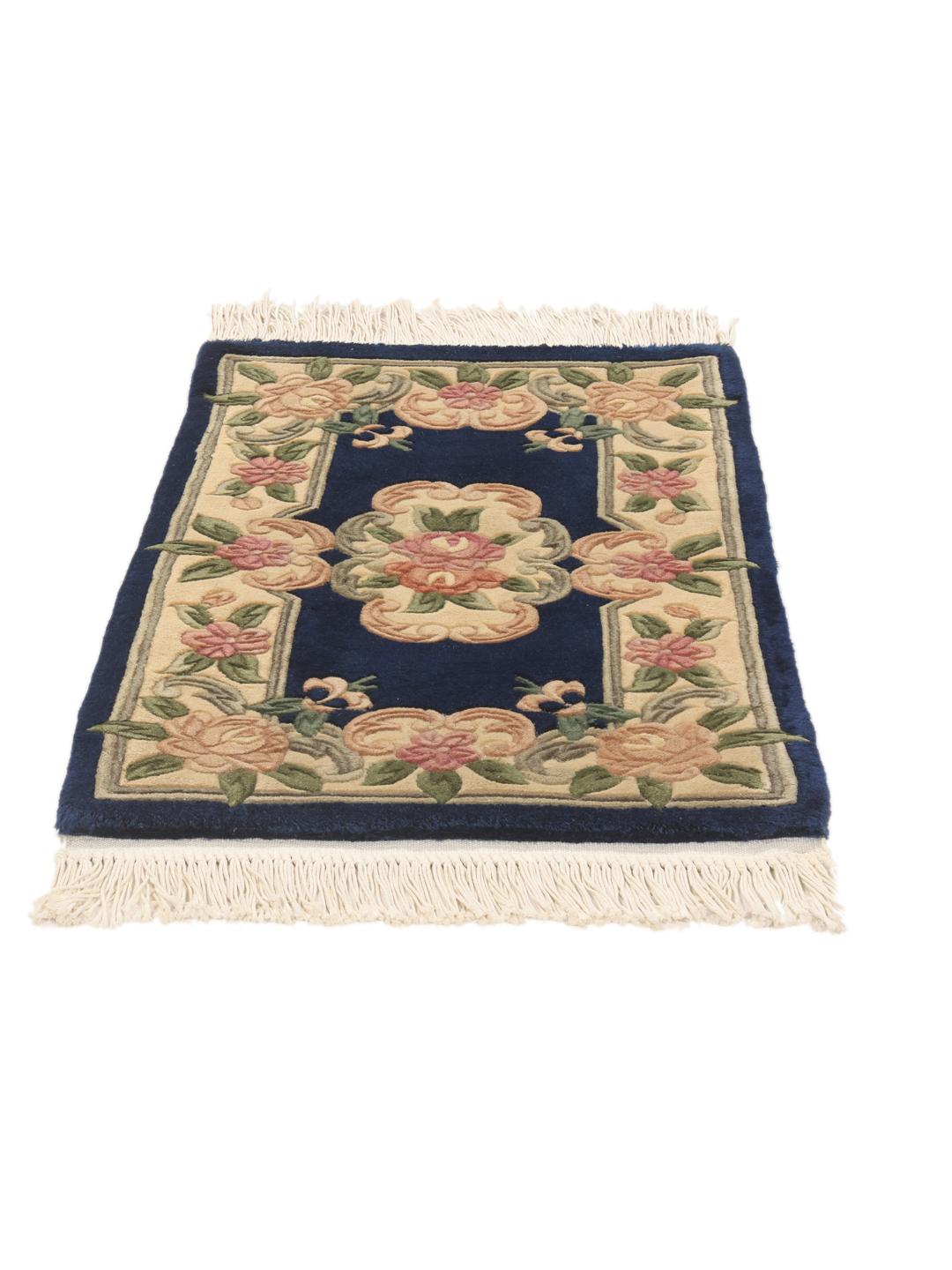 A rectangular, hand-knotted Chinese rug with a blue field and cream floral border.