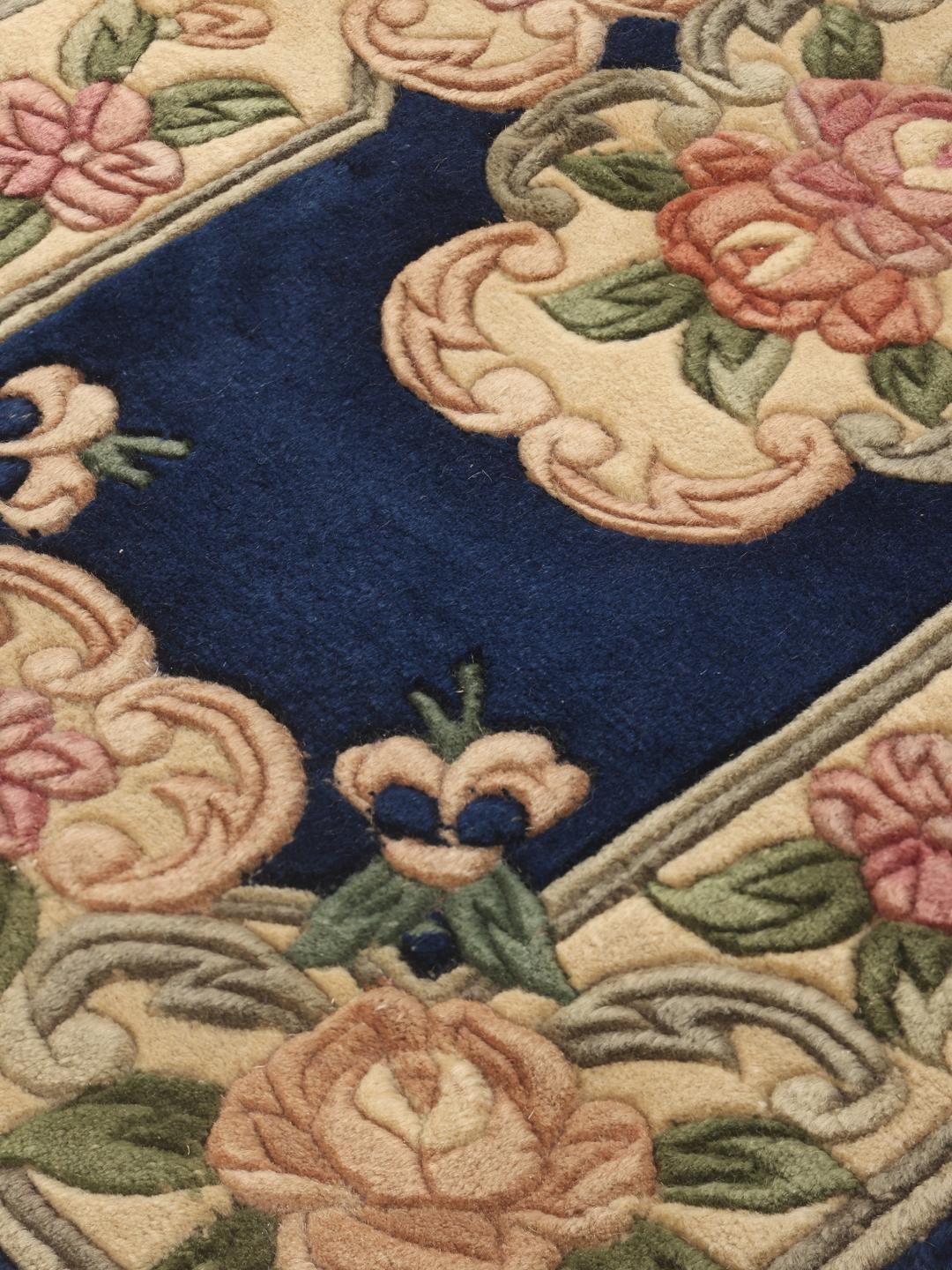 A rectangular, hand-knotted Chinese rug with a blue field and cream floral border.