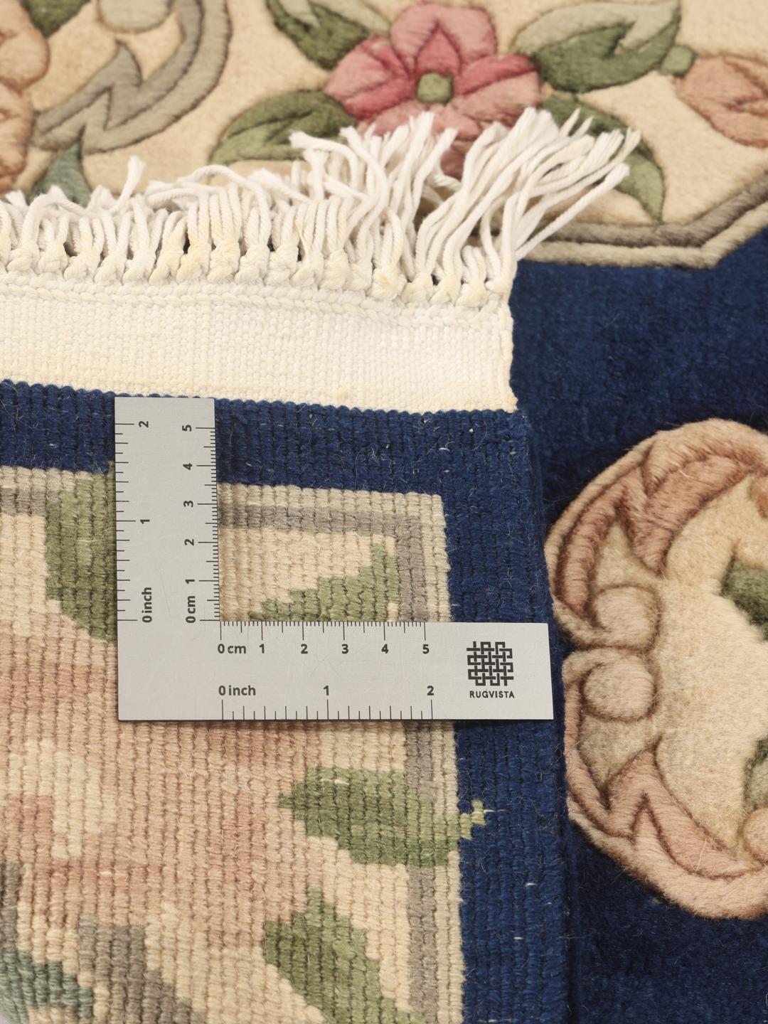 A rectangular, hand-knotted Chinese rug with a blue field and cream floral border.