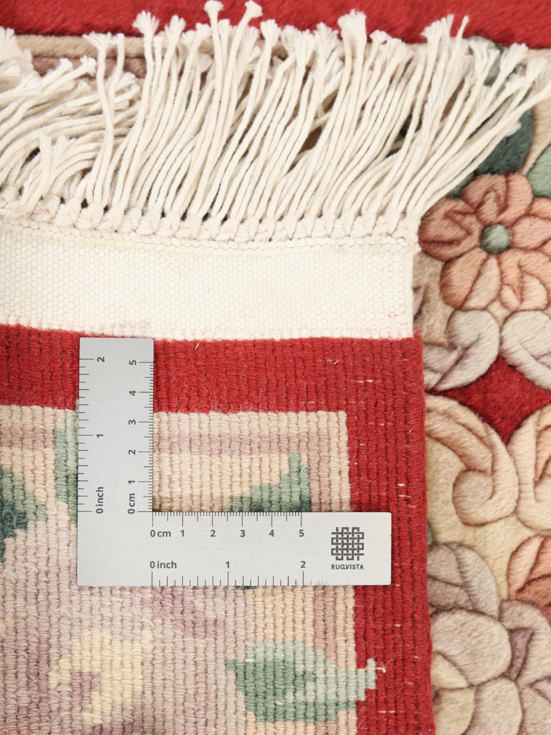 Un tapis chinois floral noué main dans des tons rouge et beige.