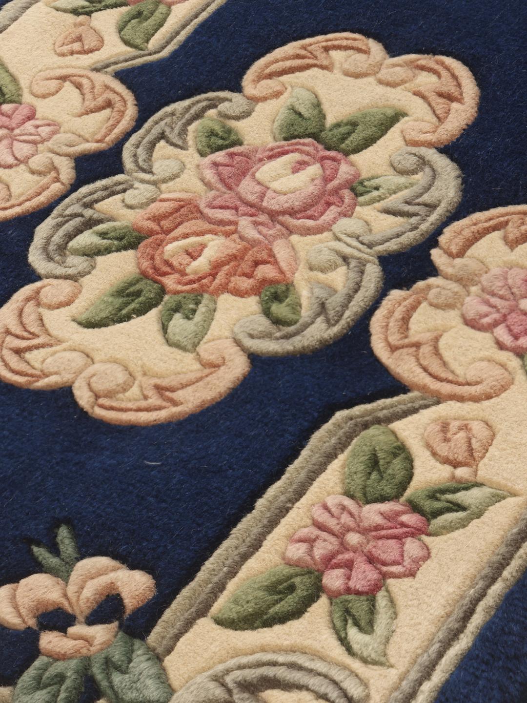 A hand-knotted floral Chinese rug with a deep blue field and cream border.