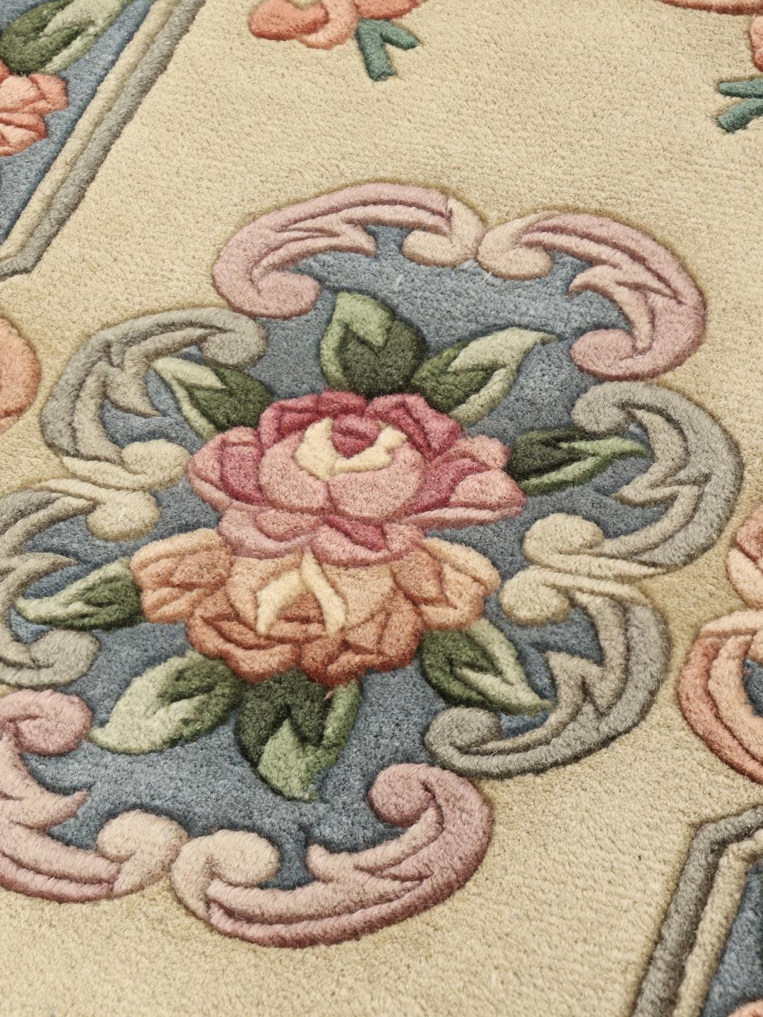 Een rechthoekig Chinees tapijt met een bloemdesign in beige, blauw en roze.
