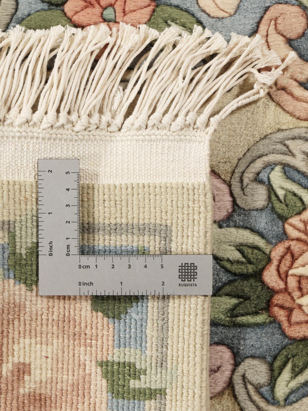 Een rechthoekig Chinees tapijt met een bloemdesign in beige, blauw en roze.