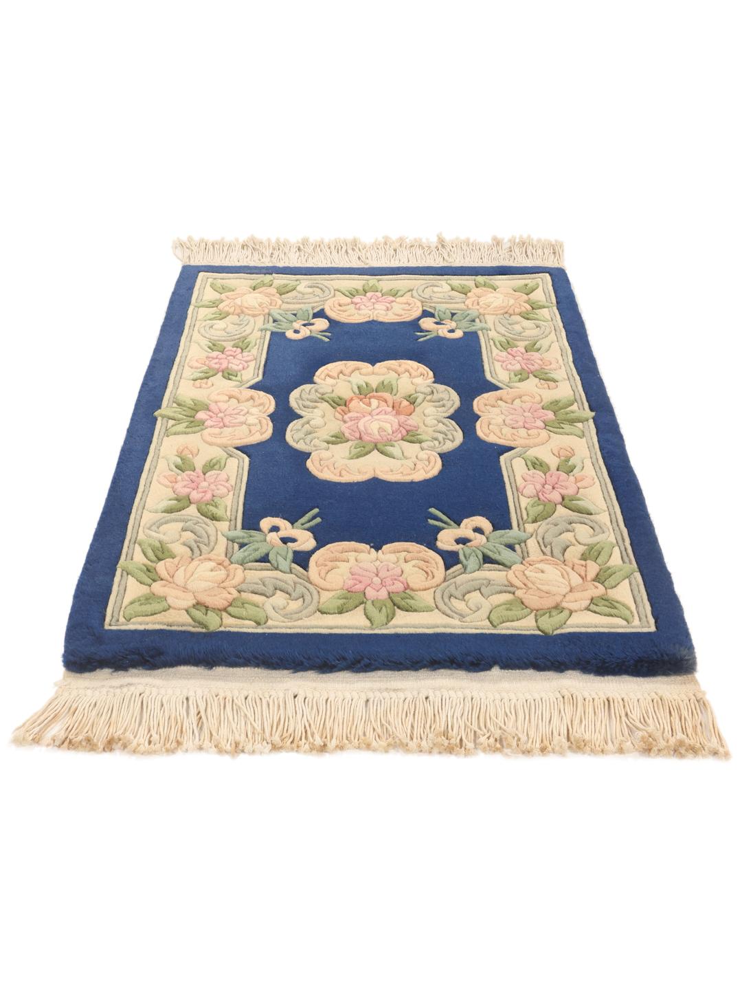 Een handgeknoopt Chinees tapijt met een diepblauw veld en verfijnde bloemmotieven.