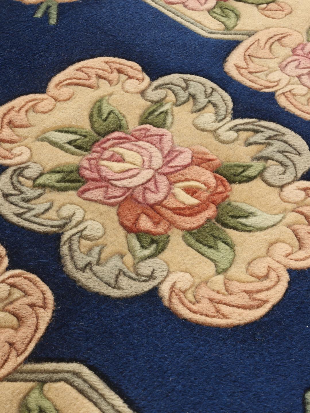 Een handgeknoopt Chinees tapijt met een diepblauw veld en verfijnde bloemmotieven.