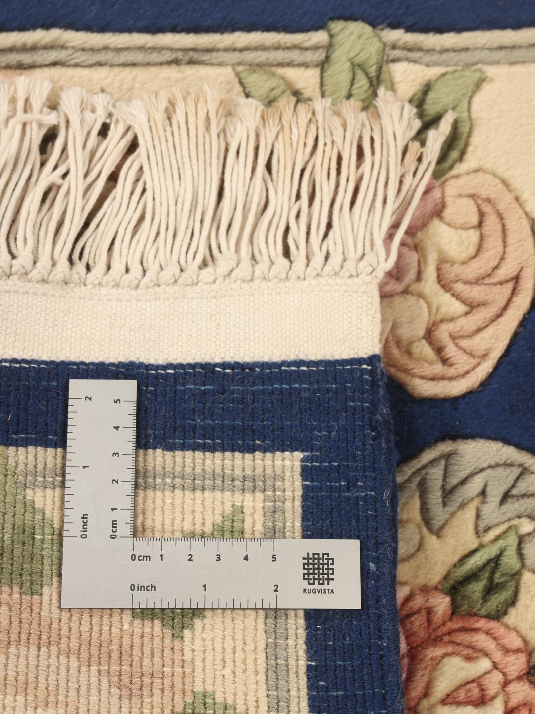 Een handgeknoopt Chinees tapijt met een diepblauw veld en verfijnde bloemmotieven.