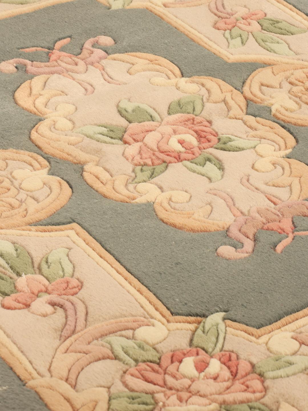 Håndknyttet kinesisk tæppe med et blomstermønster i grønne og beige toner.
