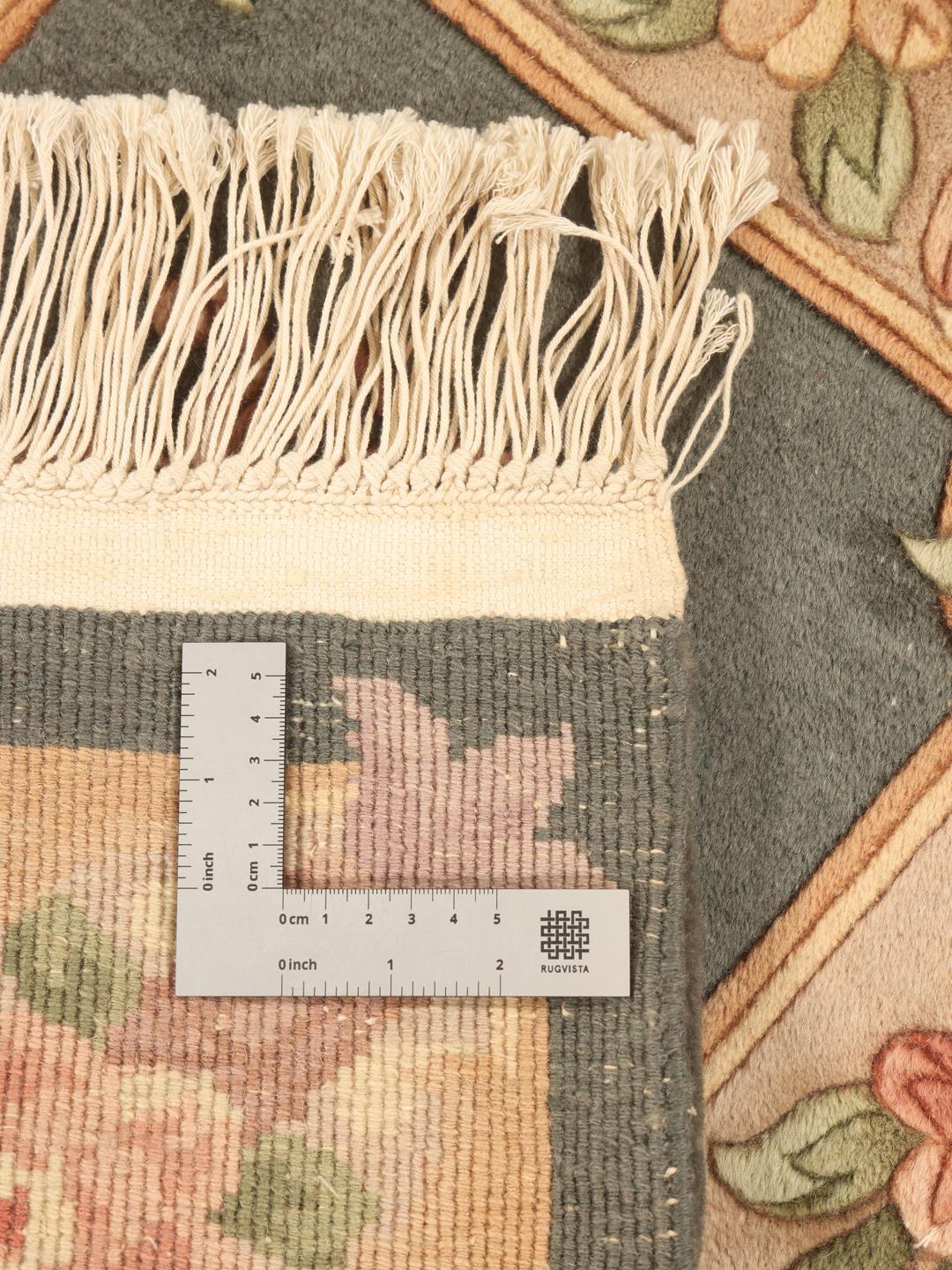 Håndknyttet kinesisk tæppe med et blomstermønster i grønne og beige toner.