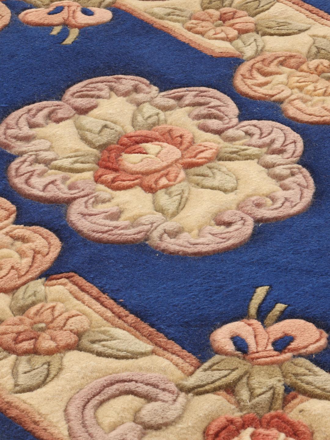 A rectangular hand-knotted rug from China with a blue field and floral pattern.