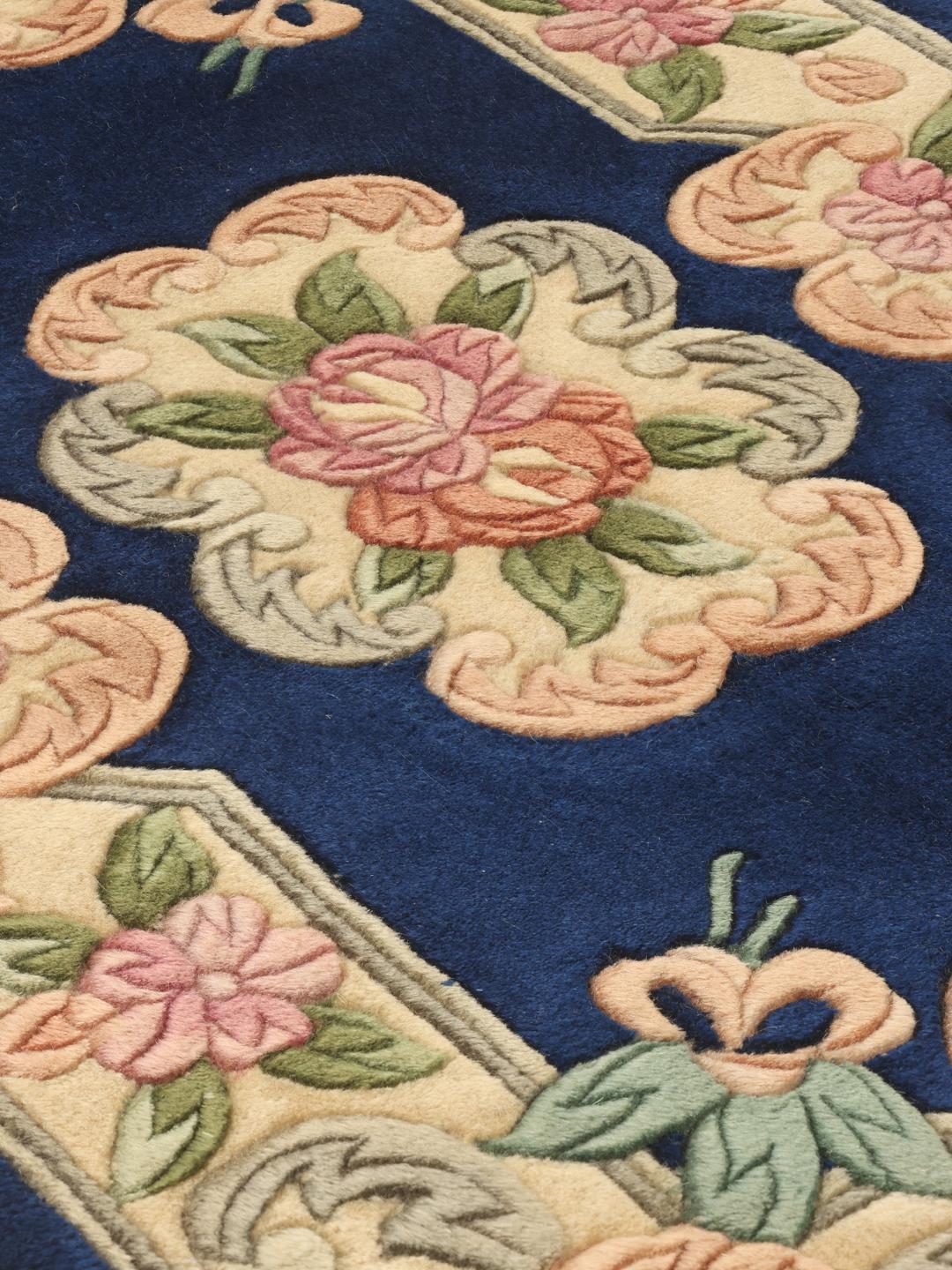Hand-knotted Chinese rug with floral motifs in blue and soft pastel tones.