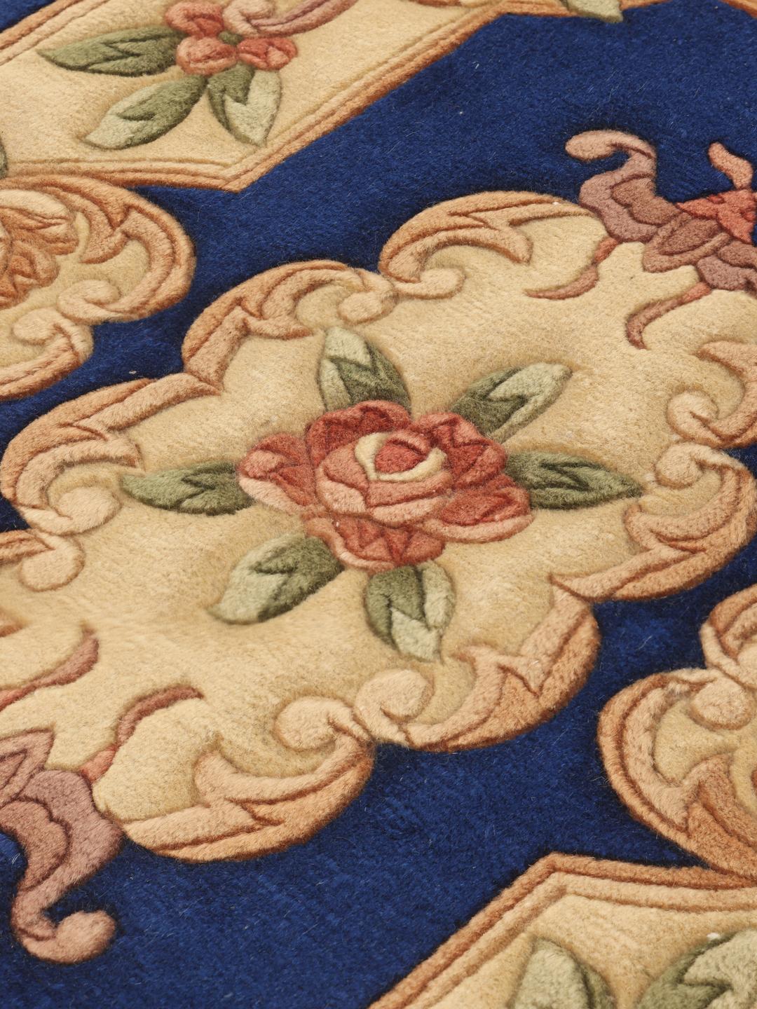 Et rektangulært håndlavet tæppe fra Kina med en blå bund og blomstermønster.