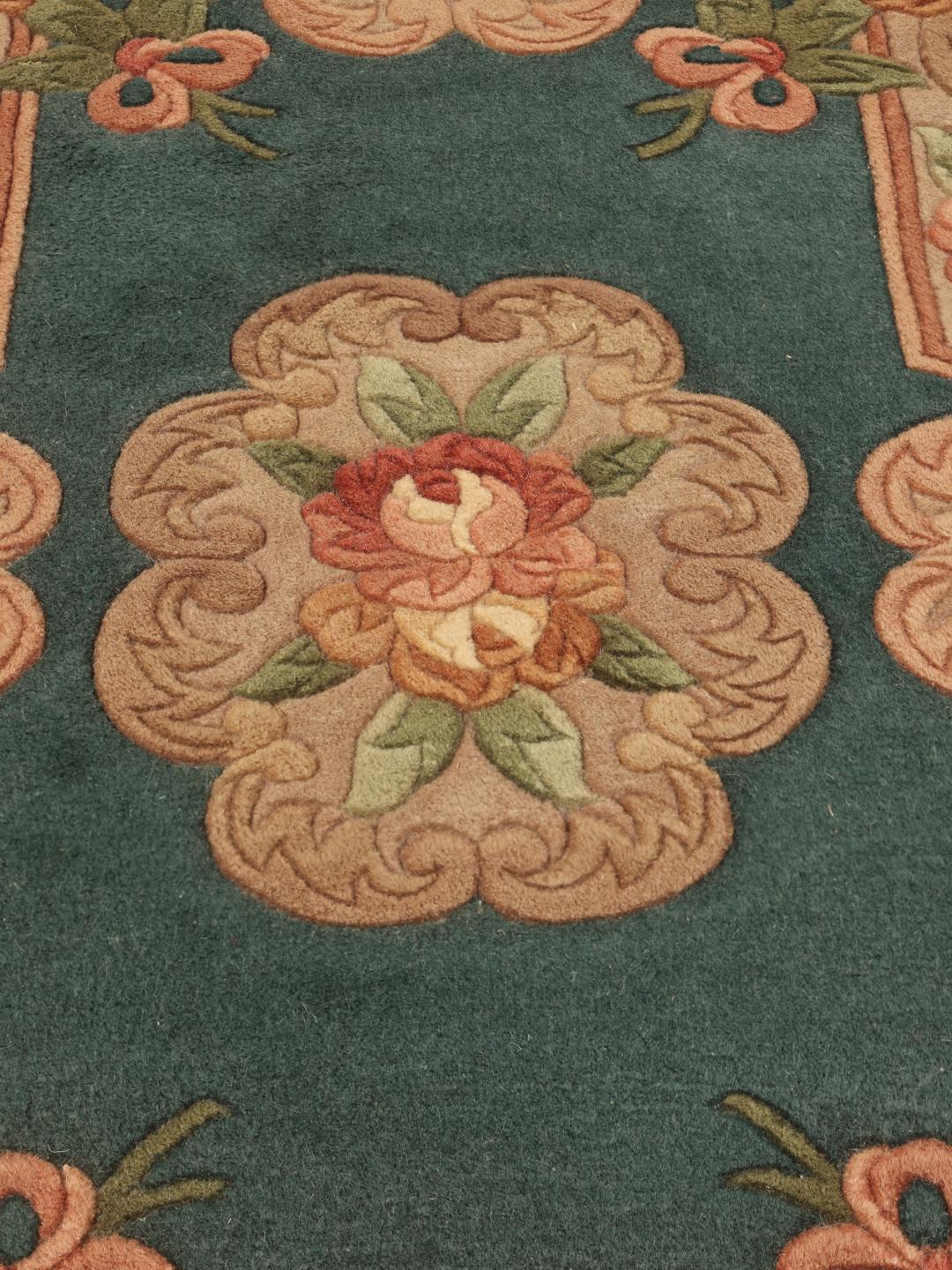A small, one-of-a-kind Chinese hand-knotted rug with a teal background and floral patterns.