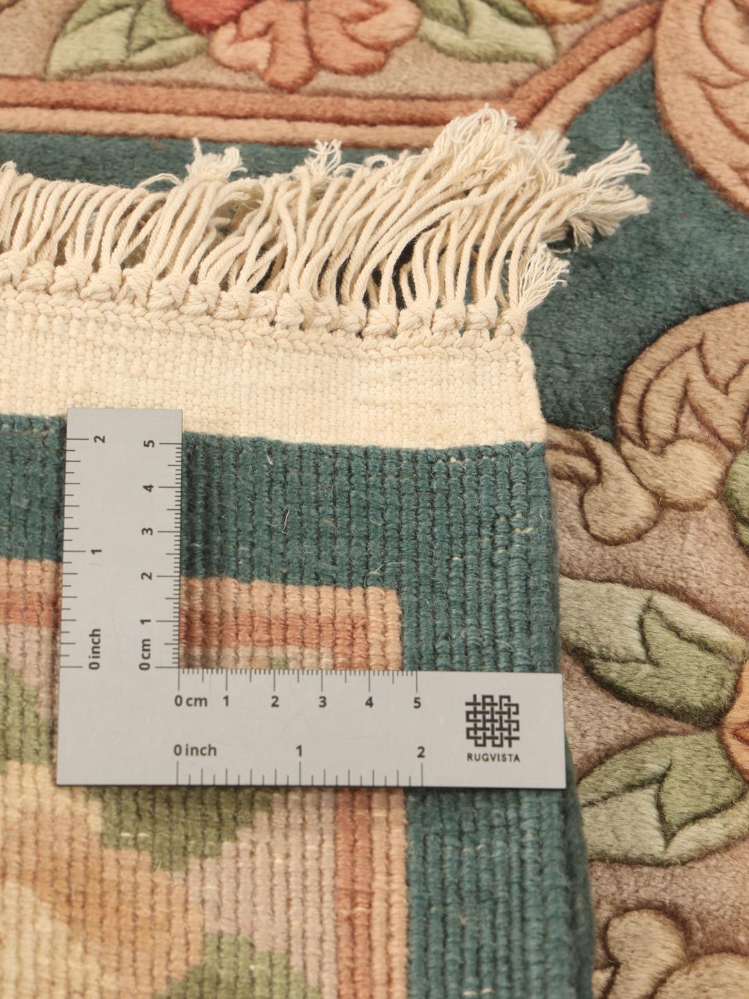 A small, one-of-a-kind Chinese hand-knotted rug with a teal background and floral patterns.