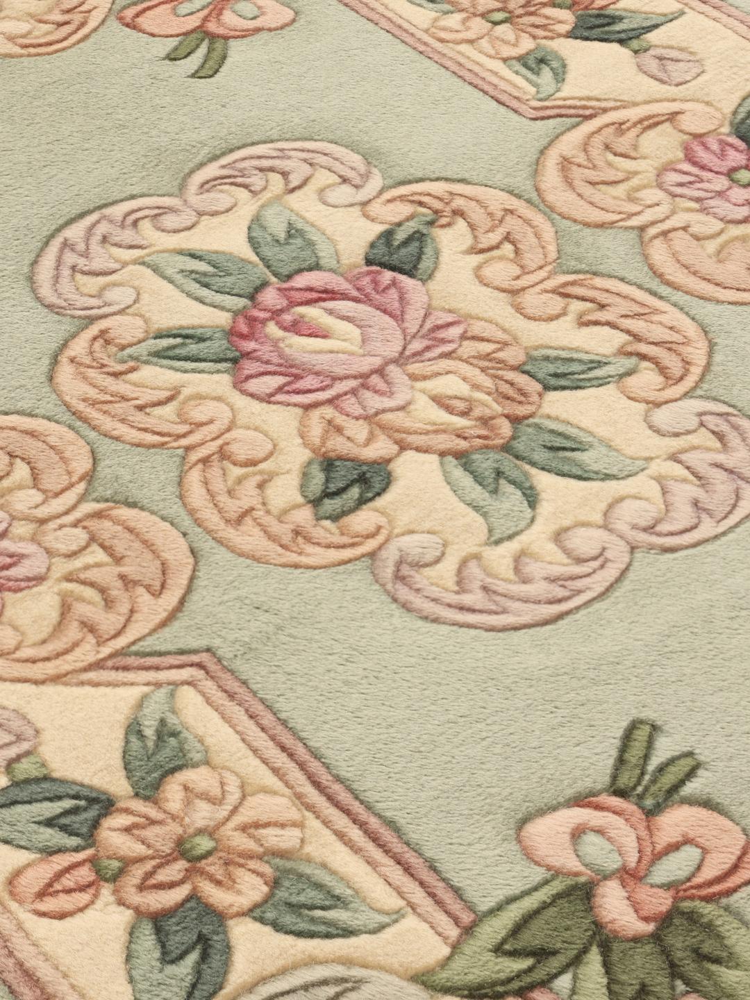 Et rektangulært håndlavet kinesisk tæppe med blomstermotiver i lysegrønne og sarte rosa nuancer.