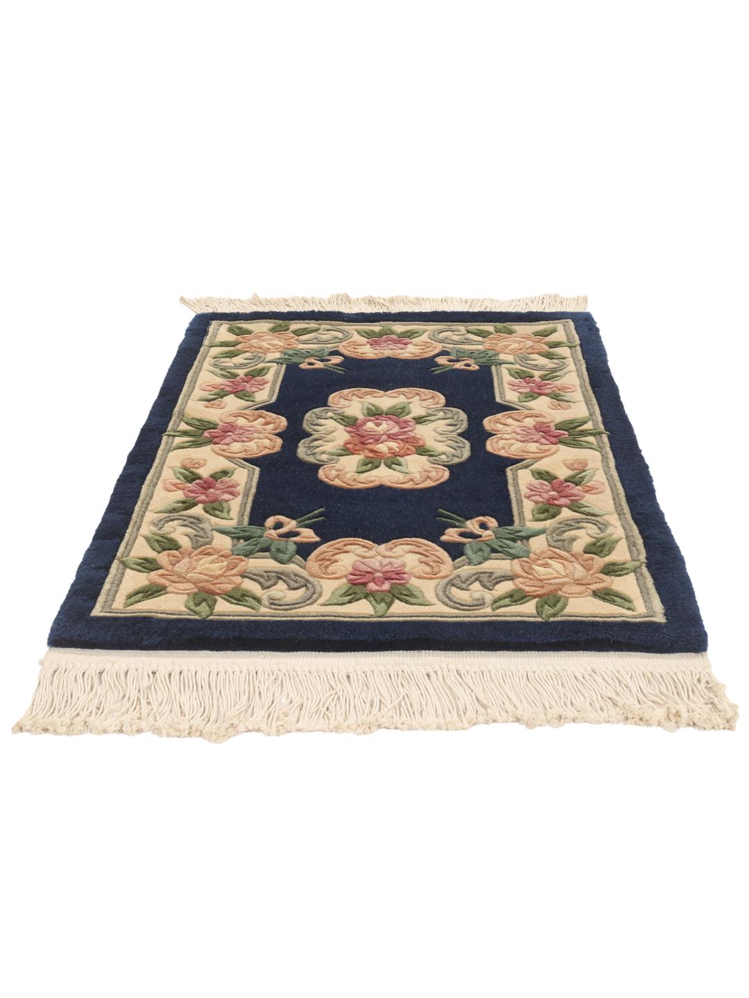A hand-knotted Chinese rug with floral motifs on a deep blue background.
