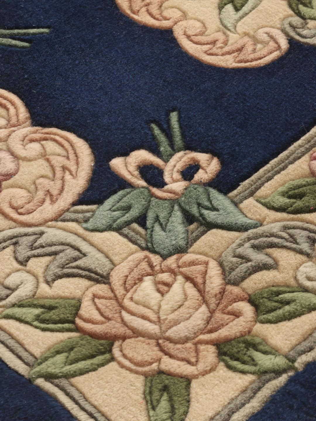 A hand-knotted Chinese rug with floral motifs on a deep blue background.