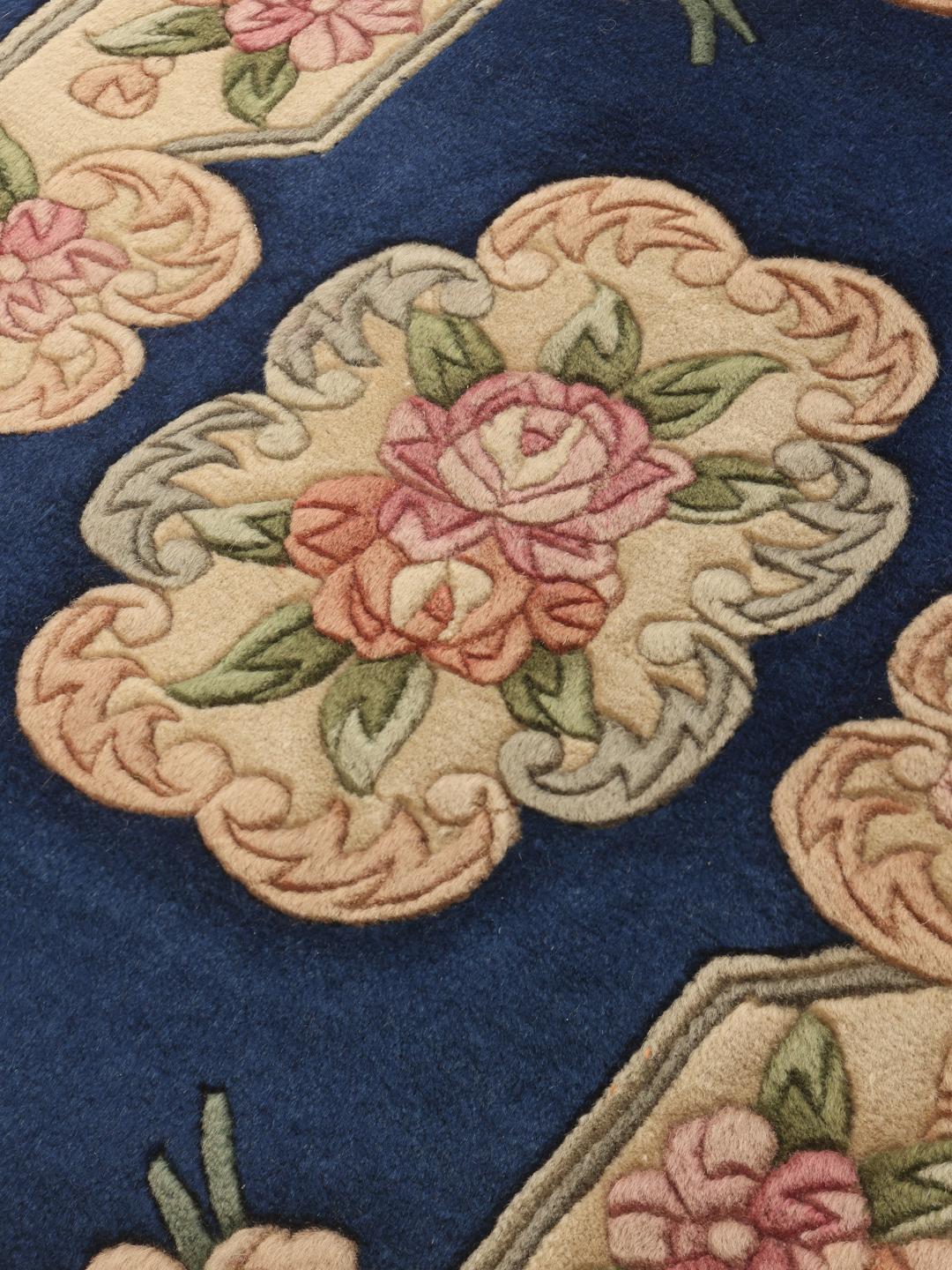 A rectangular Chinese rug featuring a blue field with delicate floral patterns in pink and green.