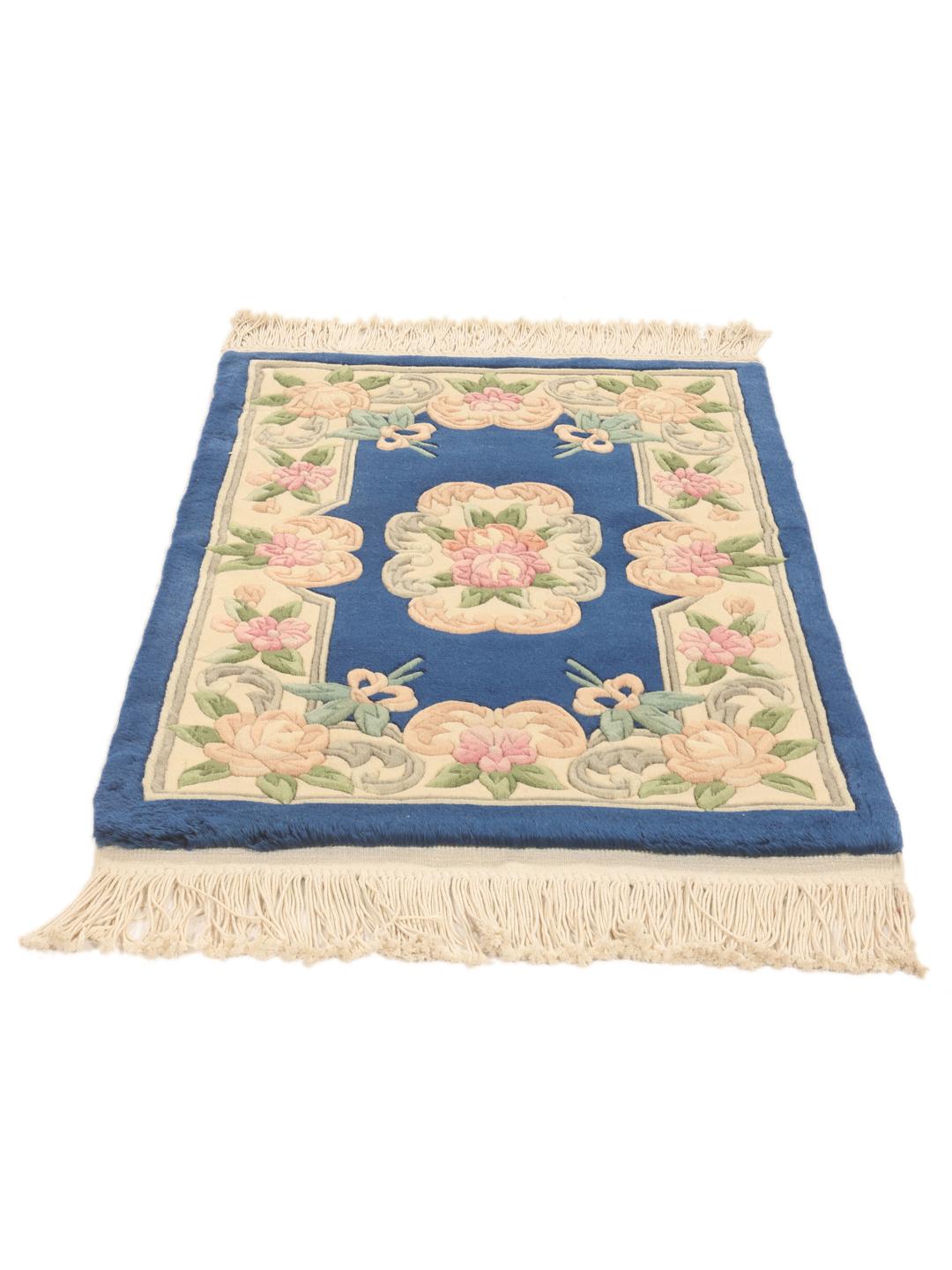 A rectangular hand-knotted Chinese rug with a floral pattern in blue and cream.