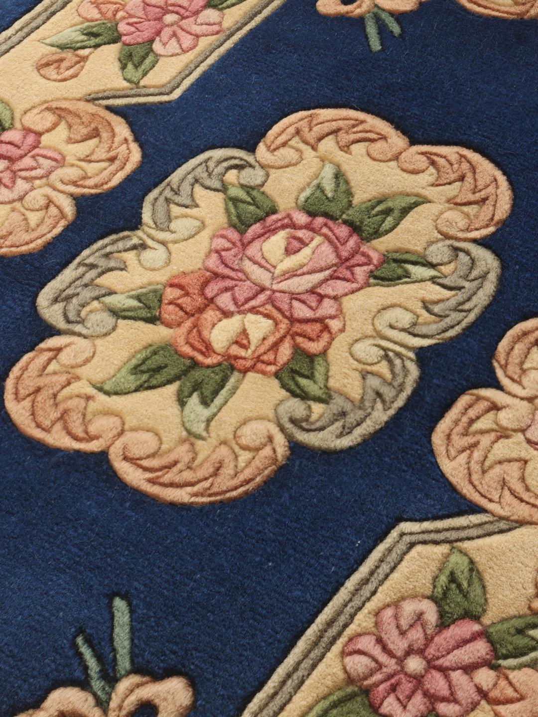 A rectangular hand-knotted Chinese rug with a floral pattern in blue and cream.