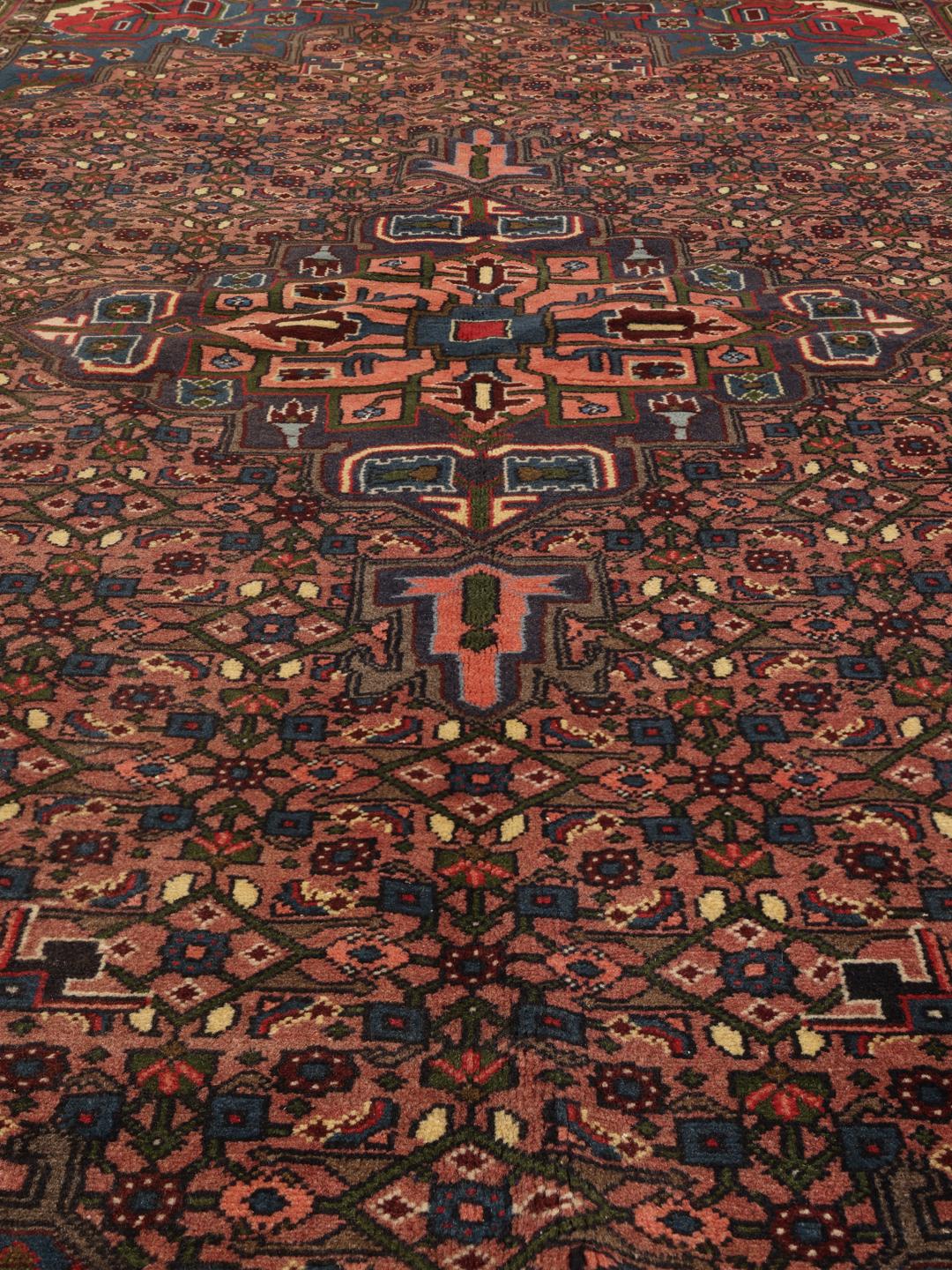 Een handgeknoopt Koliai-tapijt met complexe geometrische motieven in rode en blauwe tinten uit het Midden-Oosten.