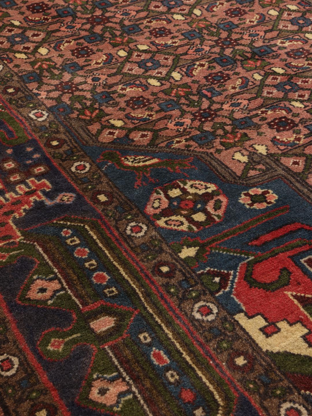 Een handgeknoopt Koliai-tapijt met complexe geometrische motieven in rode en blauwe tinten uit het Midden-Oosten.