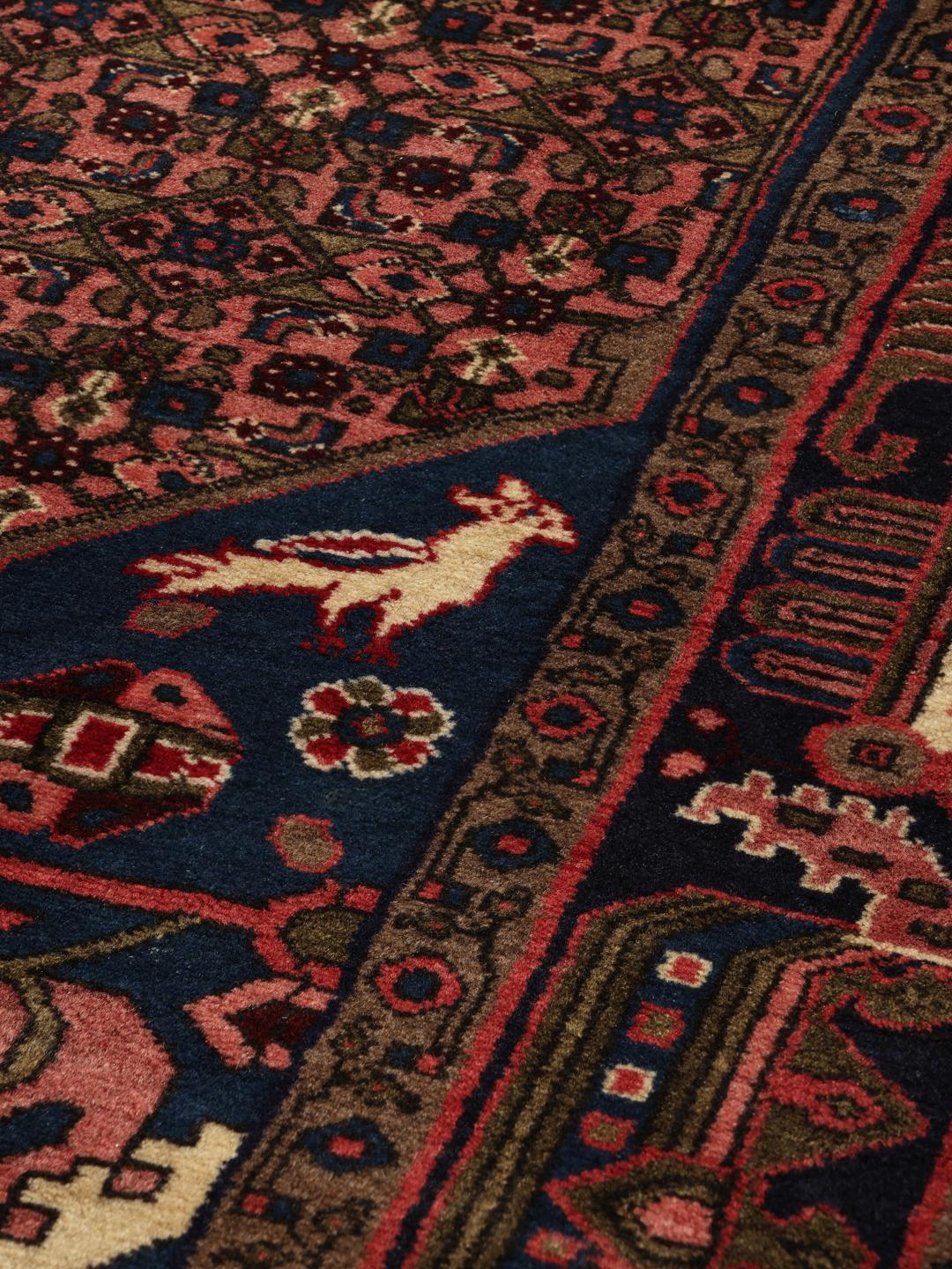 Een handgeknoopt Koliai-tapijt uit het Midden-Oosten met een donkerblauw en rood kleurenpalet.