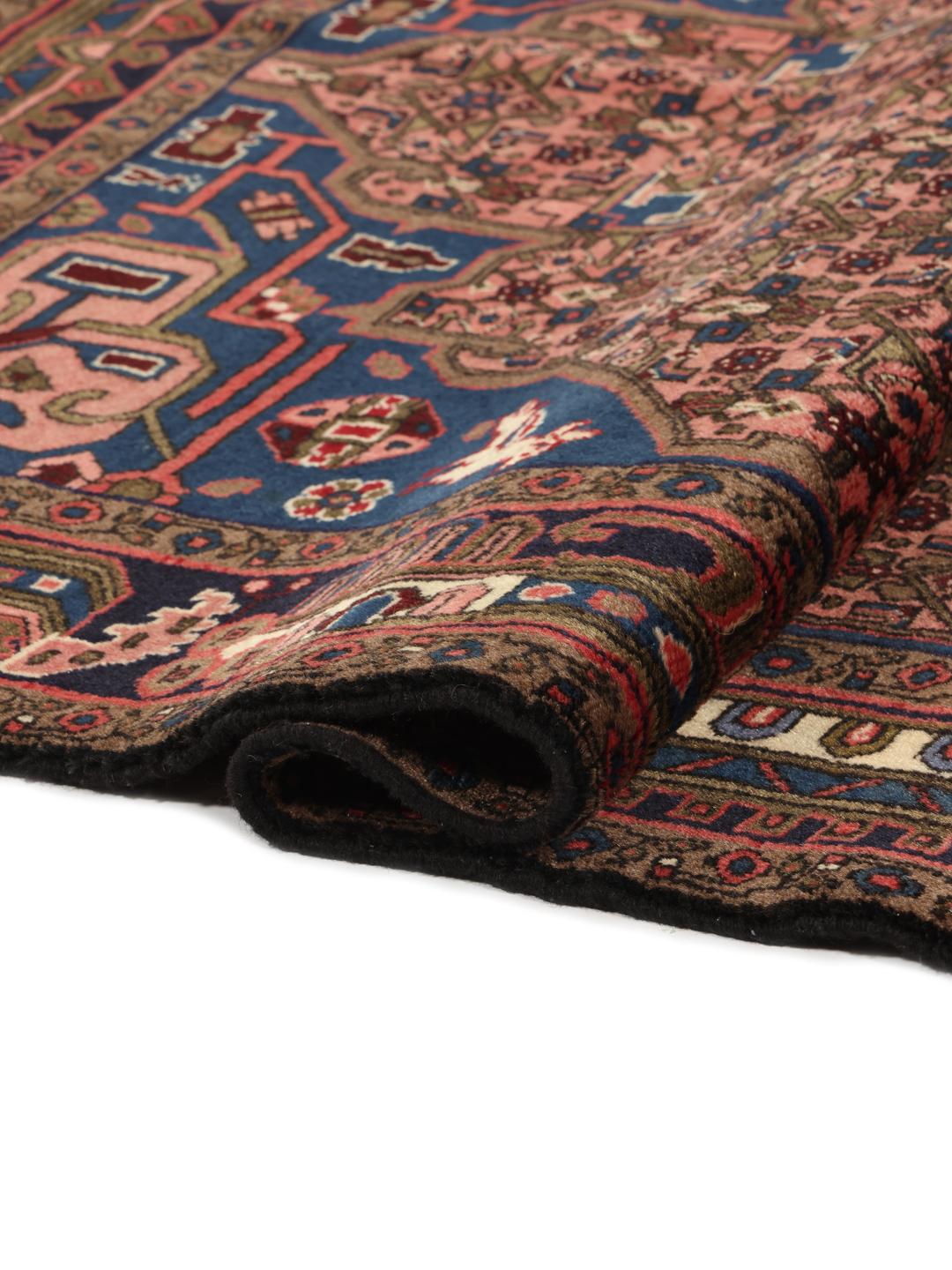 Een handgeknoopt Koliai-tapijt uit het Midden-Oosten met een donkerblauw en rood kleurenpalet.