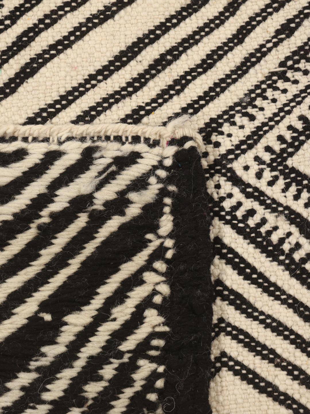 Hand-woven Moroccan High Atlas rug with geometric black and off-white patterns.