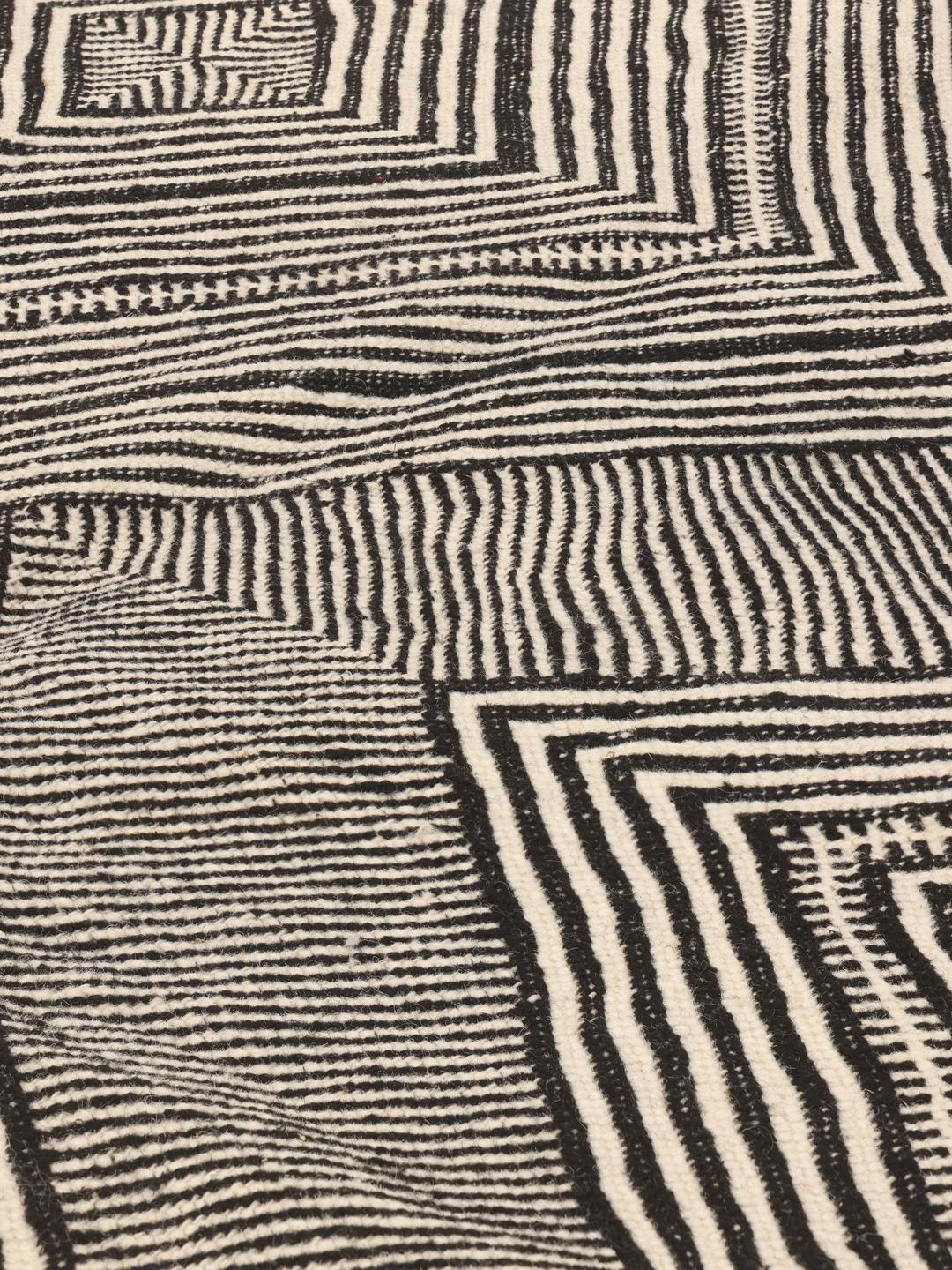 Een handgeweven Marokkaans kleed met een zwart-wit geometrisch ruitenpatroon