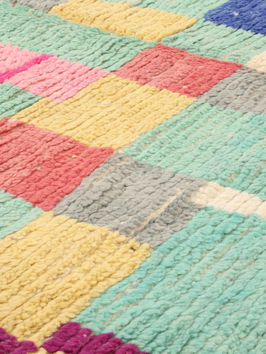 Handgeknoopt Marokkaans tapijt met een levendig veelkleurig geometrisch patroon op een groenblauwe achtergrond