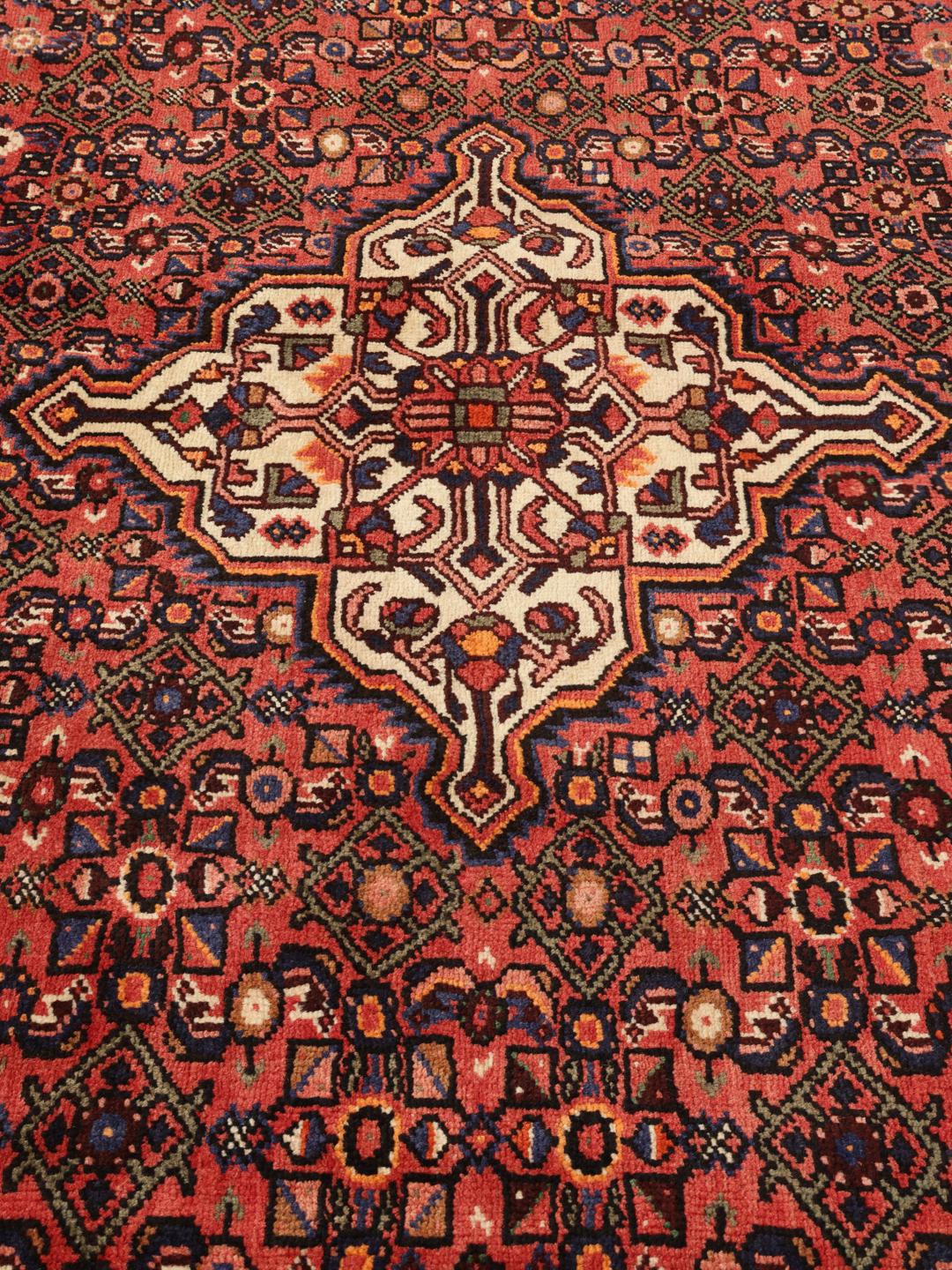 A hand-knotted Hosseinabad rug from the Middle East with a rich red field and central medallion.