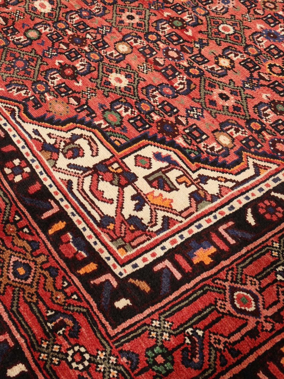 A hand-knotted Hosseinabad rug from the Middle East with a rich red field and central medallion.