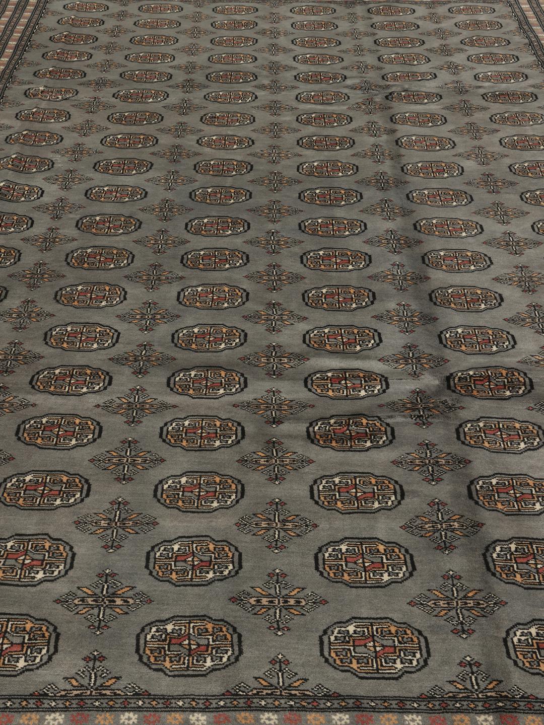 A hand-knotted Pakistan Bokhara rug in grey with traditional repeating motifs.