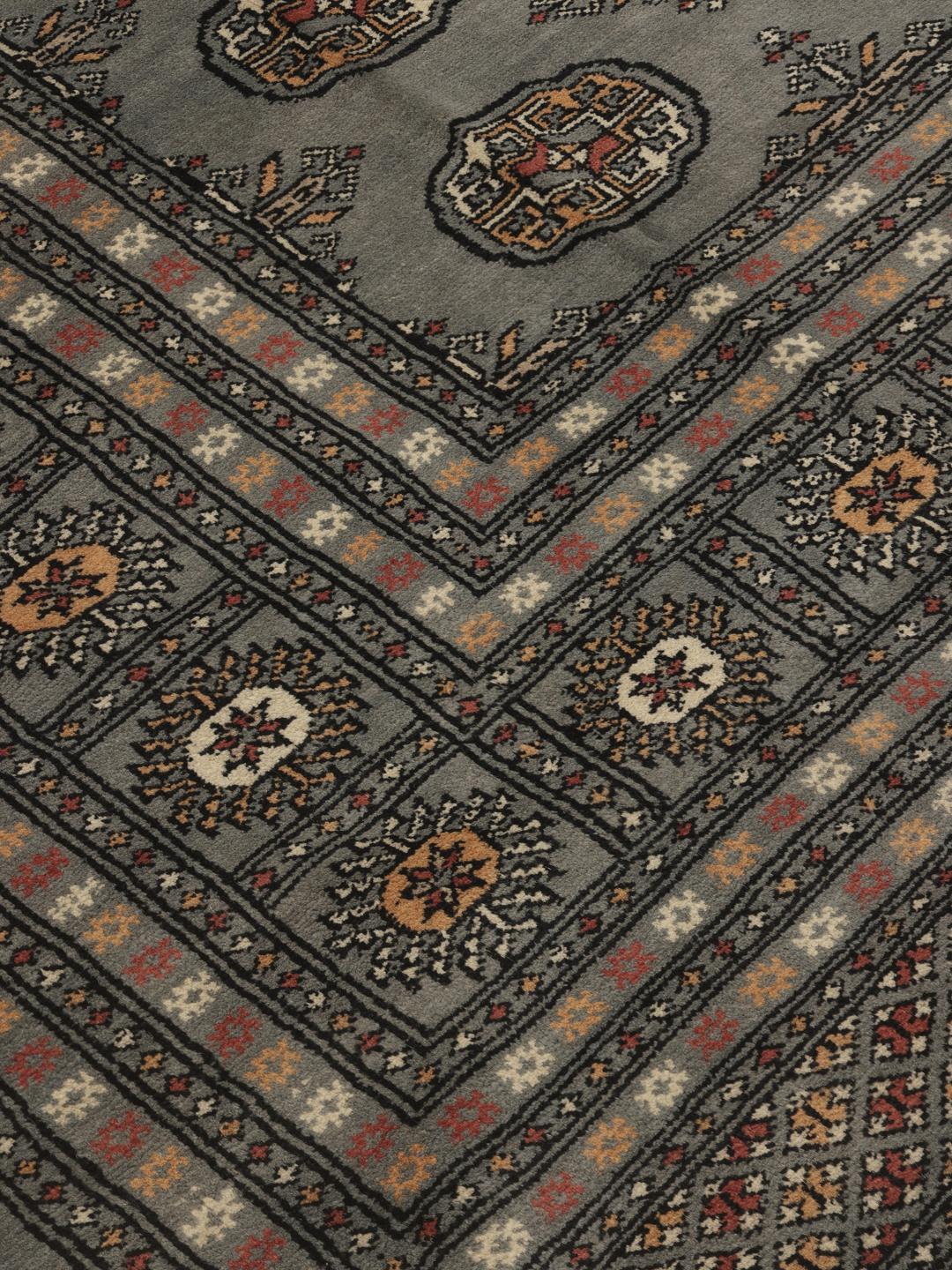 A hand-knotted Pakistan Bokhara rug in grey with traditional repeating motifs.