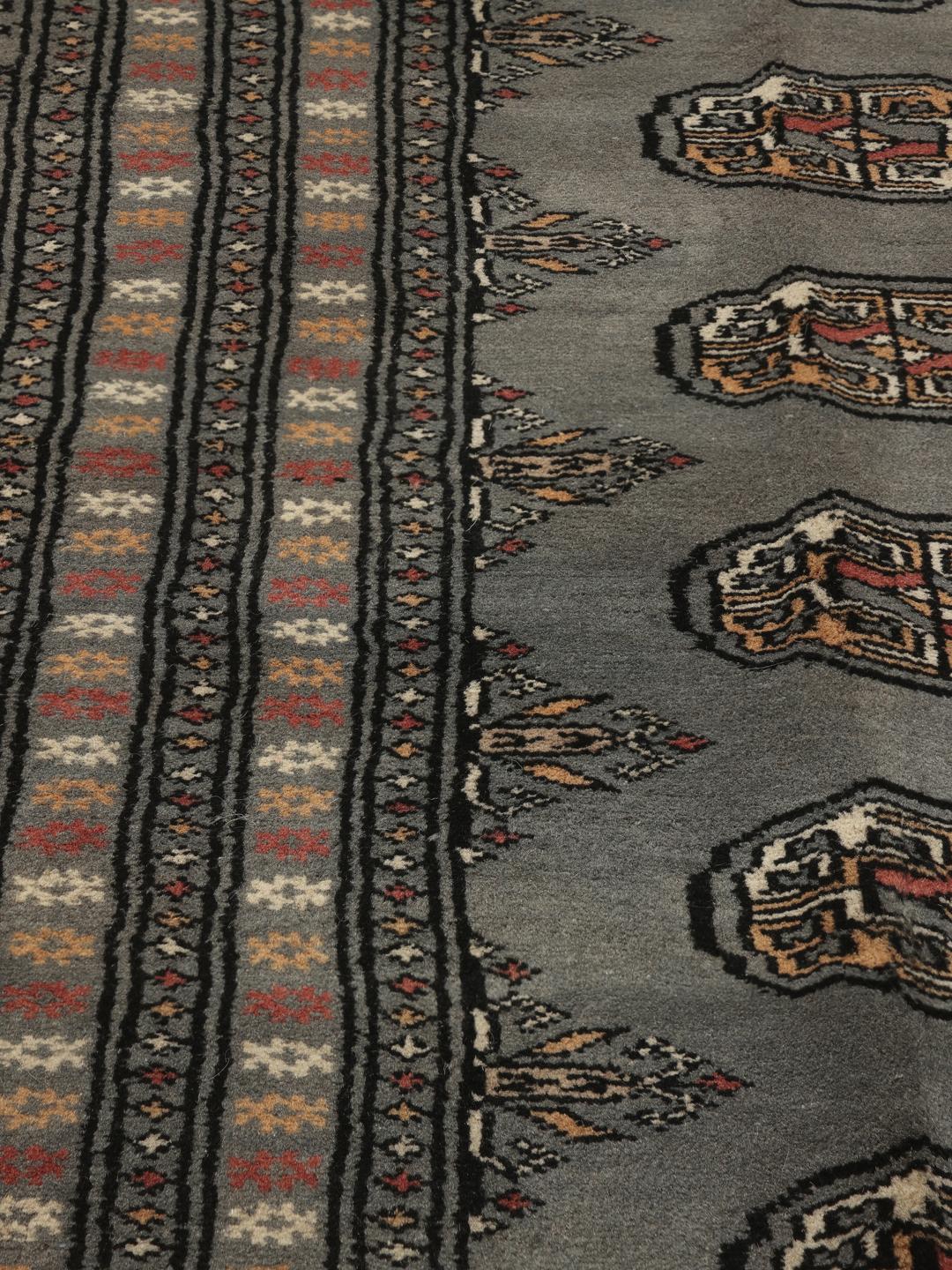 A hand-knotted Pakistan Bokhara rug in grey with traditional repeating motifs.