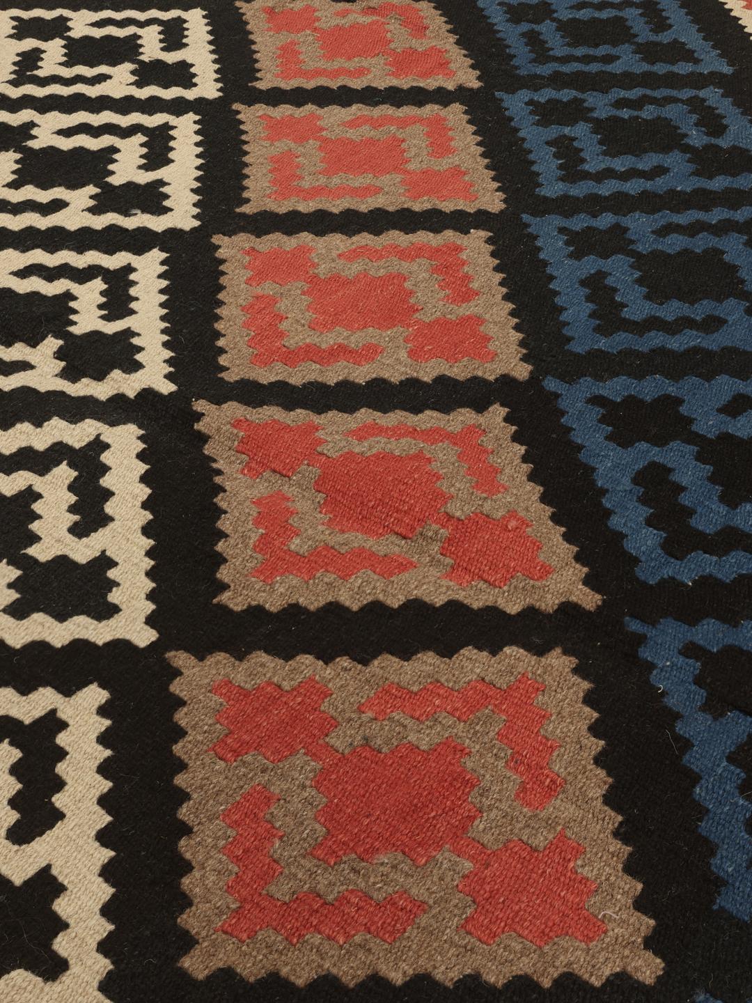 Handgeweven Ghashghai-kelimkleed met veelkleurige geometrische patronen op een zwart veld.