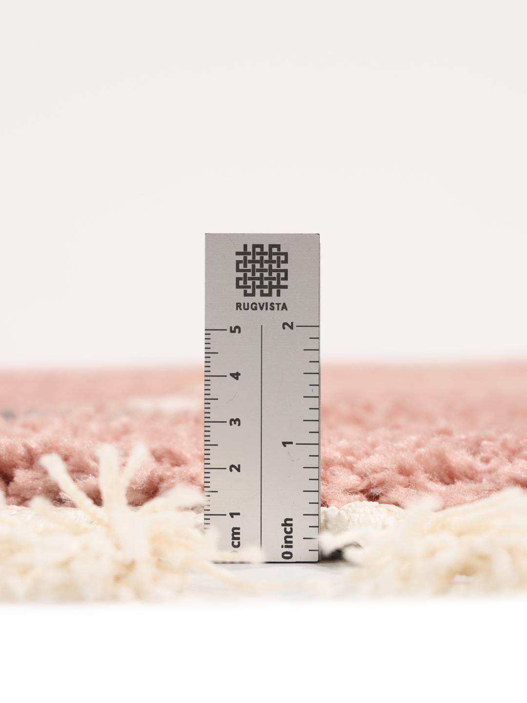 Rond roze vloerkleed met een stippenpatroon en franjes