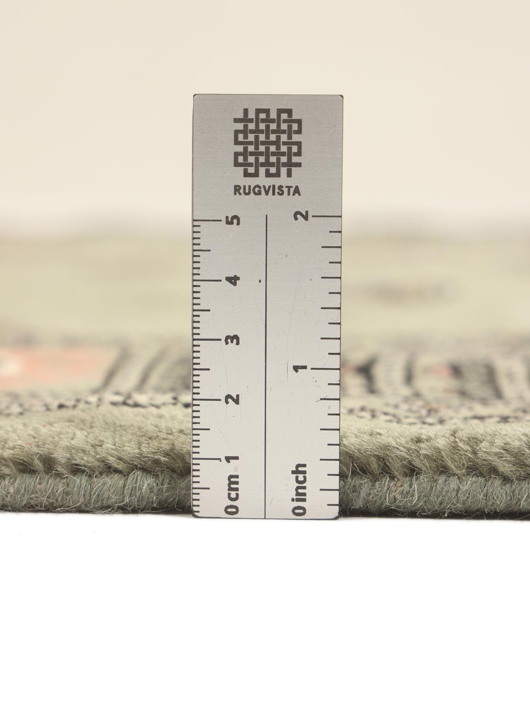 A hand-knotted green Pakistan Bokhara rug with traditional repeating motifs.