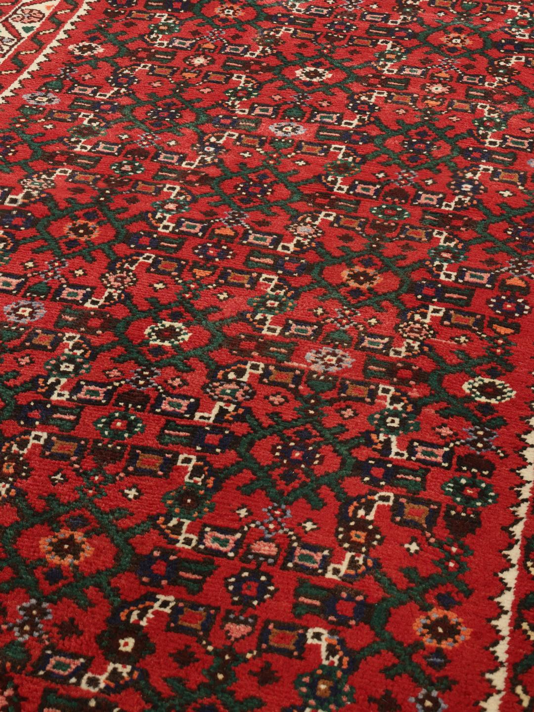 Een handgeknoopte rode Hosseinabad loper met verfijnde traditionele patronen.