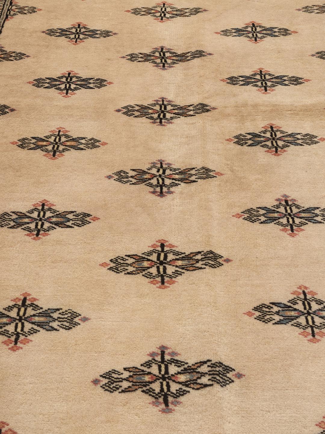 Een handgeknoopt Pakistan Bokhara tapijt met een beige veld en traditionele motieven.