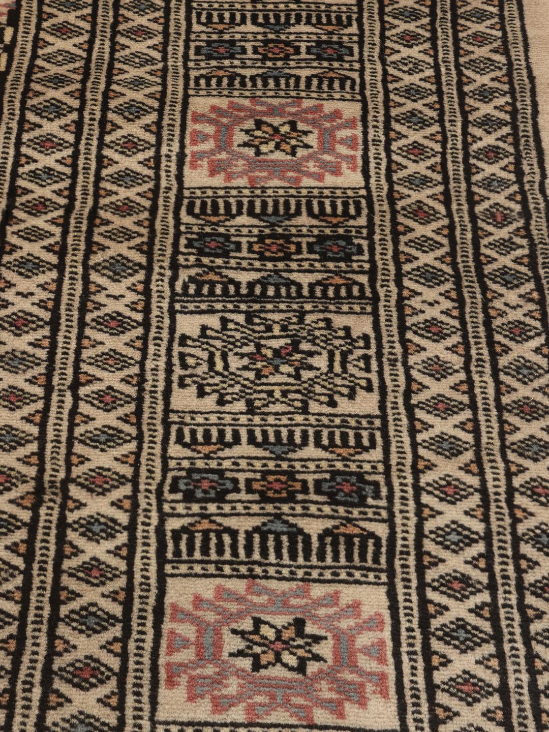 Een handgeknoopt Pakistan Bokhara tapijt met een beige veld en traditionele motieven.